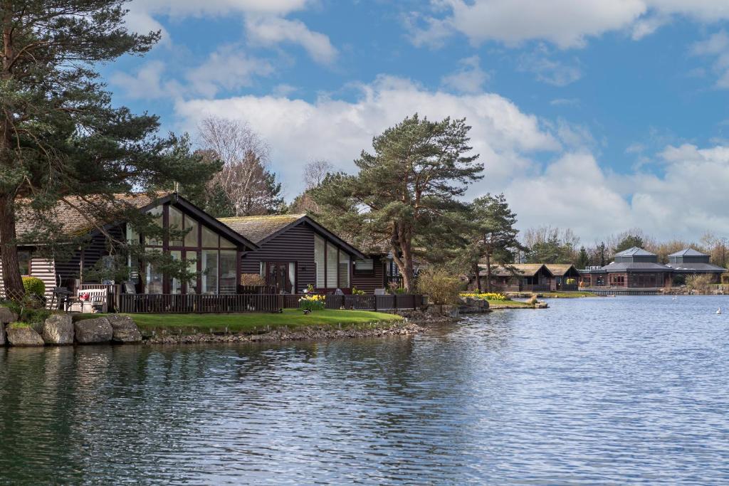 a house on the shore of a lake at Keer Lodge a lakeshore haven Pine Lake Resort in Carnforth