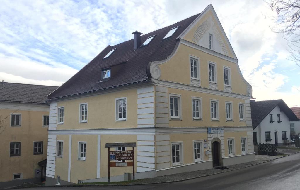 duży żółto-biały budynek z czarnym dachem w obiekcie Gästehaus Ulrichsberg w mieście Ulrichsberg
