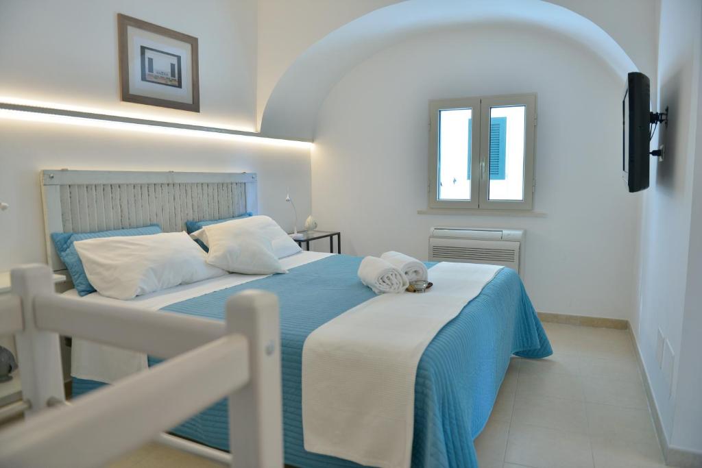 una camera da letto con un letto con lenzuola blu e una finestra di Albergo Diffuso Monopoli a Monopoli