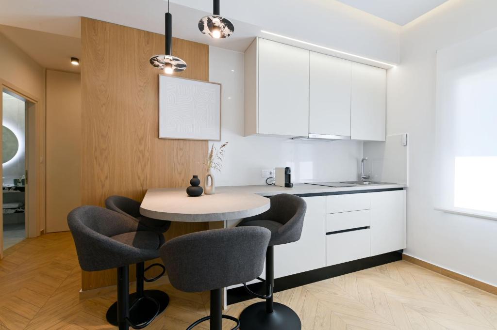 a kitchen with white cabinets and a table and chairs at Memoa Residence Preveza in Preveza