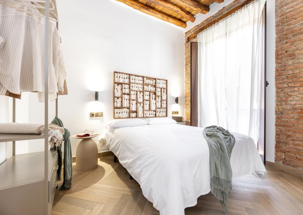 a bedroom with a white bed and a brick wall at Apartamentos El Marqués in Granada
