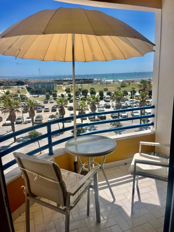 a table and chairs on a balcony with an umbrella at Paradise in Costa da Caparica