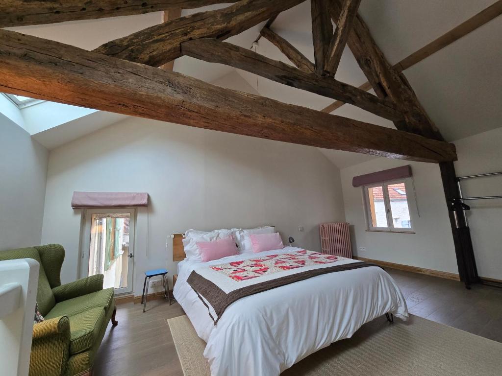 a bedroom with a large bed and a green chair at The Little Hideaway - La Petite Maison Cachée in Noyers