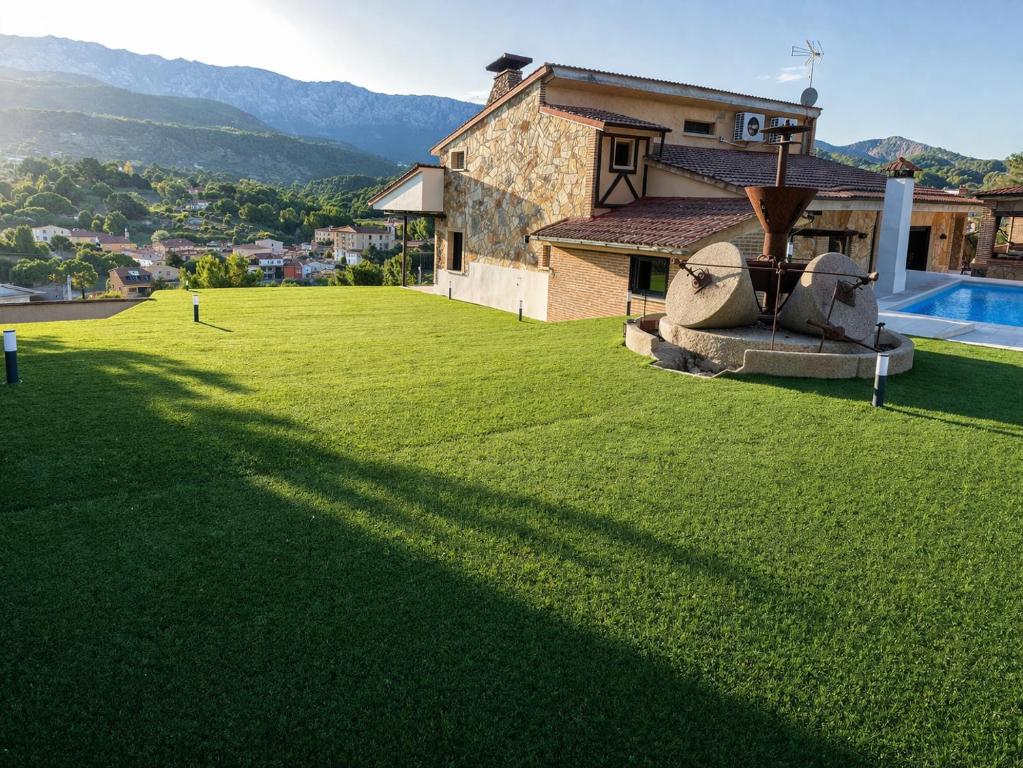 a large lawn with a house and a swimming pool at Faro de Gredos in Arenas de San Pedro