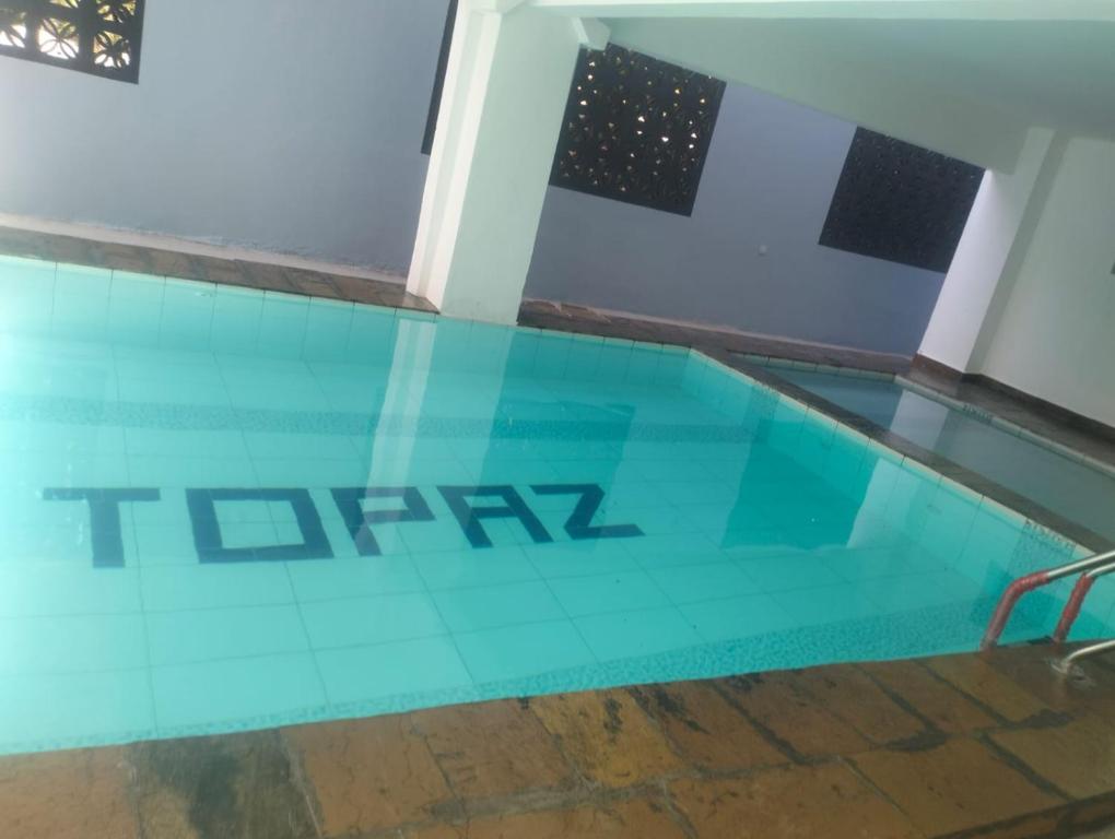 a glass swimming pool with the tarmac logo on it at Topaz Apartments Shanzu in Mombasa