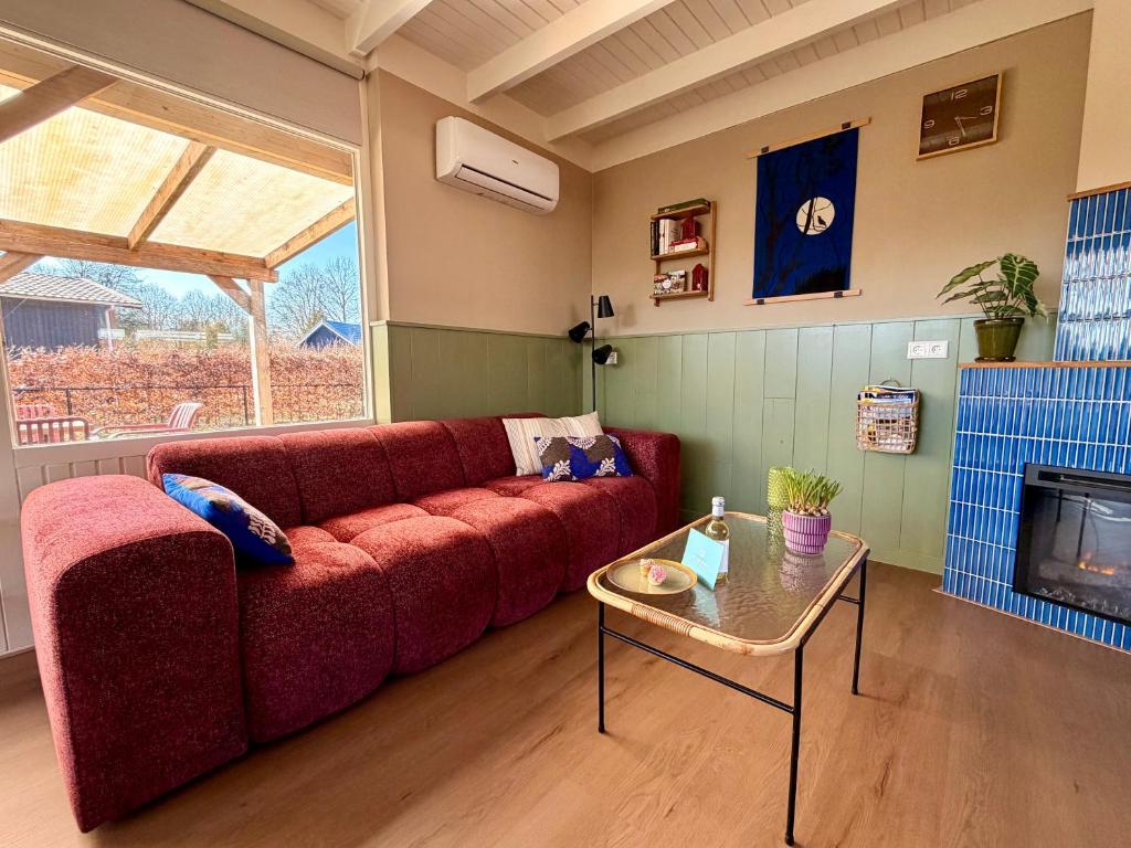 a living room with a red couch and a table at Bungalow Doris with Hot Tub | 4 persons in Gasselte