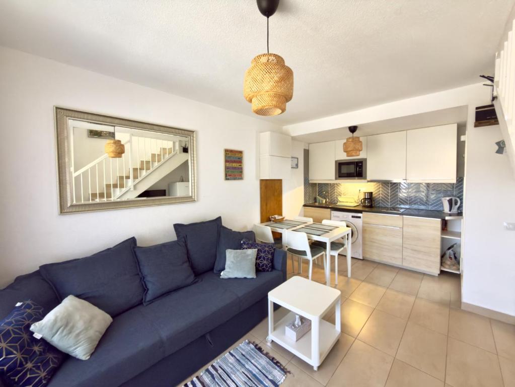 a living room with a blue couch and a kitchen at Casa Hugo in Costa Calma