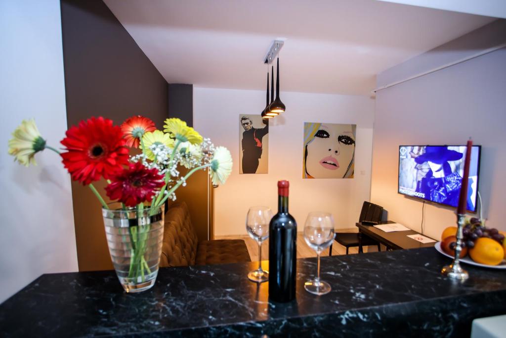una mesa con un jarrón de flores y dos copas de vino en Metropolitan Iassium Luxury Suites, en Iaşi