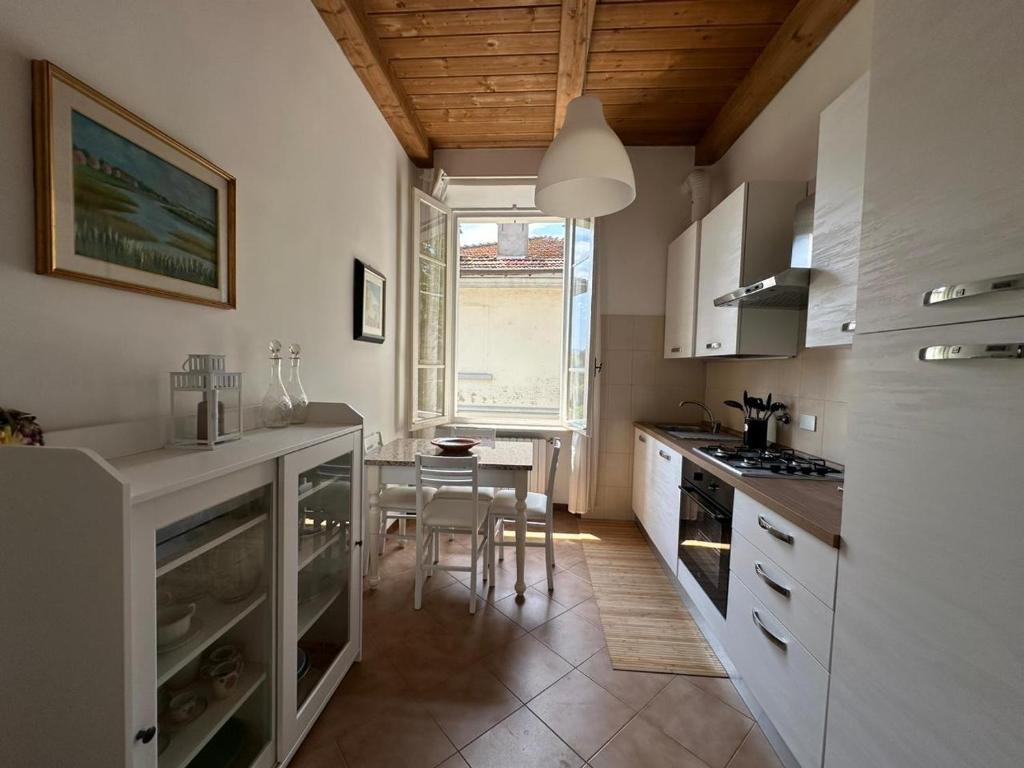 eine Küche mit weißen Schränken, einem Tisch und einem Fenster in der Unterkunft Aurea in Castrocaro Terme