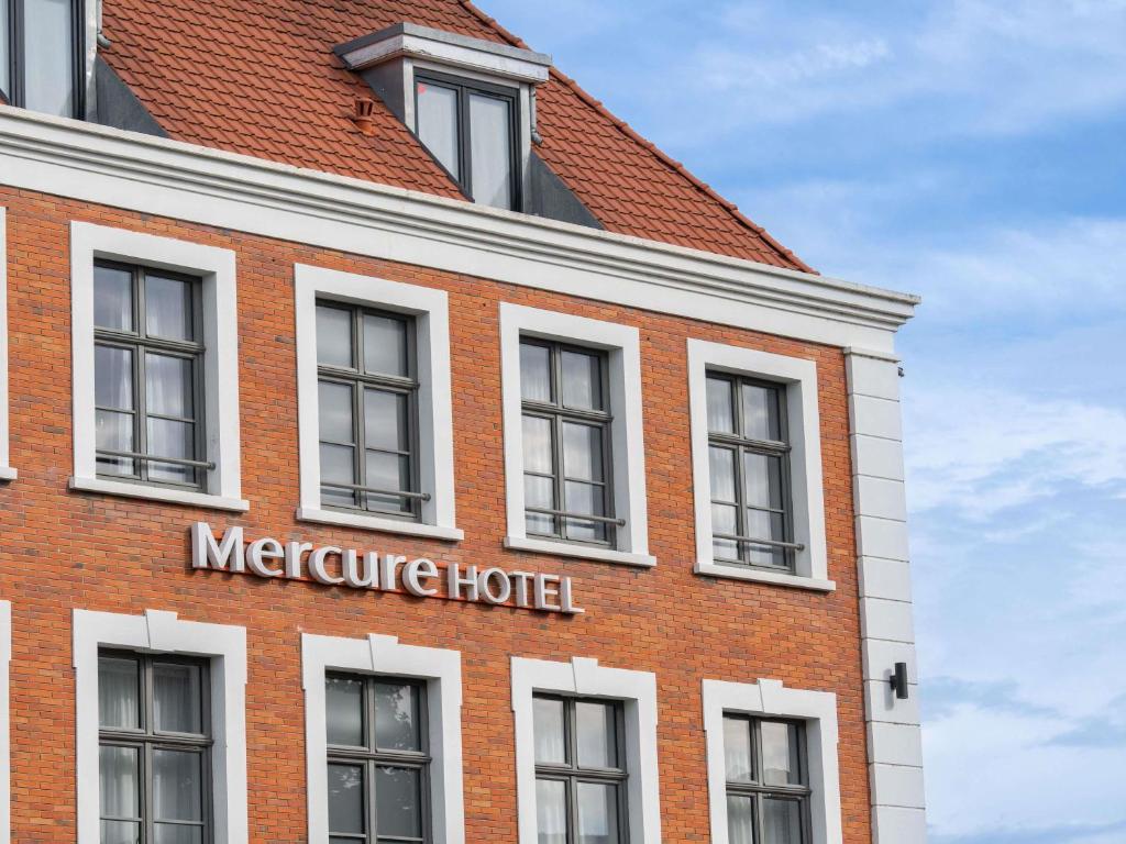 a red brick building with a mercure hotel sign on it at Mercure Saint Omer Centre Gare in Saint-Omer