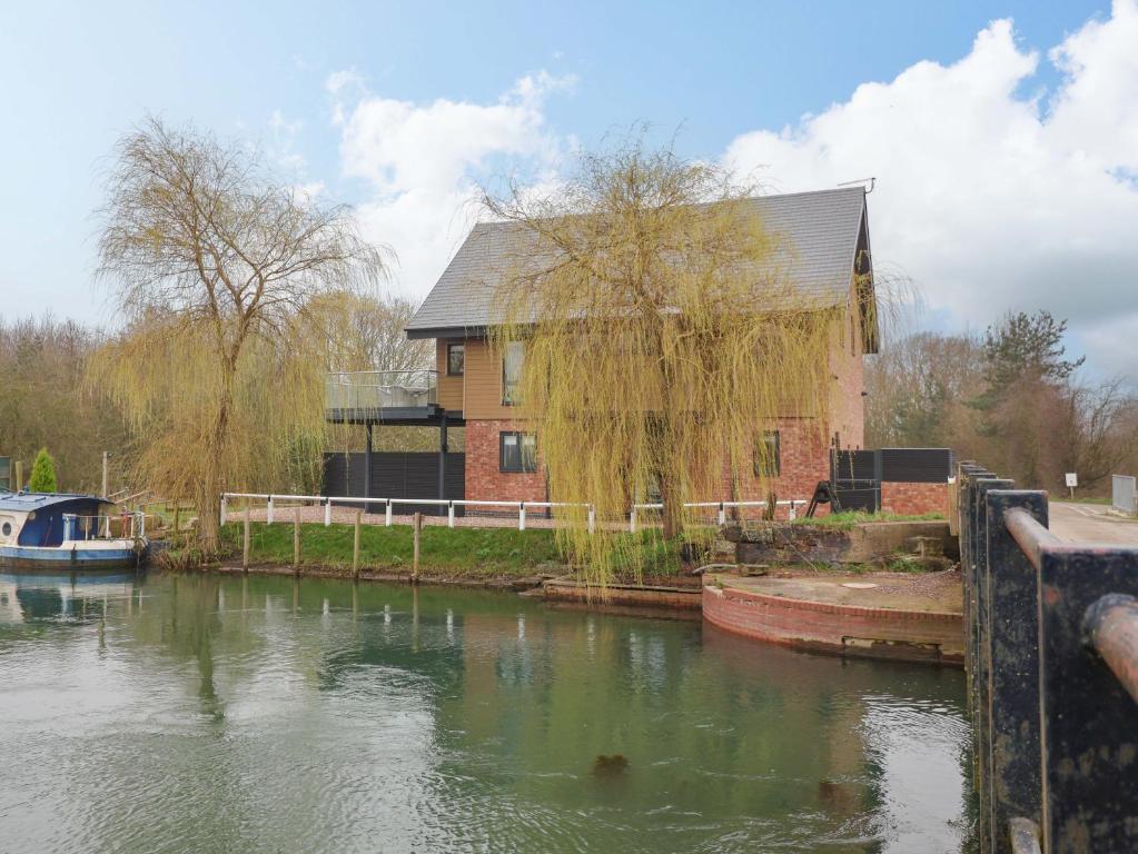 a house next to a river with a boat at Swing Bridge Cottage in Brandesburton