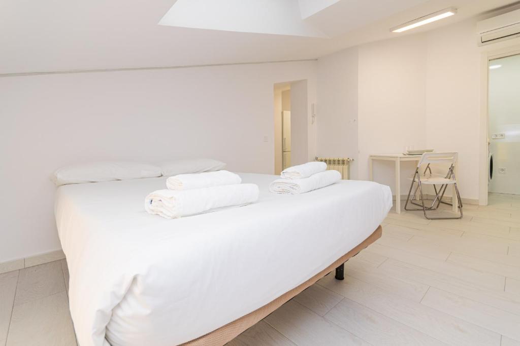 ein weißes Zimmer mit einem Bett, auf dem Handtücher liegen in der Unterkunft Still Loft in Coslada