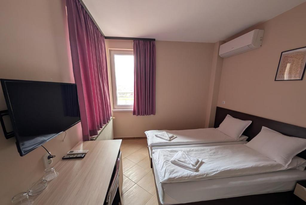 a hotel room with two beds and a flat screen tv at Hotel Poli in Blagoevgrad