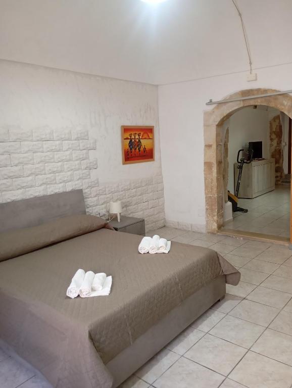 a bedroom with a bed with two slippers on it at Da Adriana NETUM in Noto