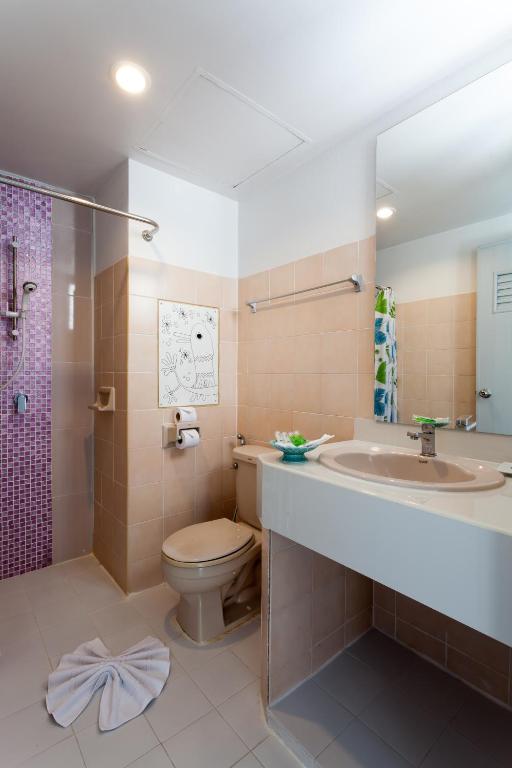 A compact bathroom with a vanity, toilet and open shower area.