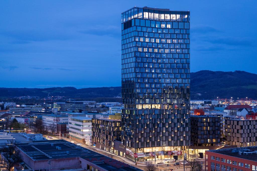 a tall glass building in a city at night at ARCOTEL Tabakfabrik Linz in Linz