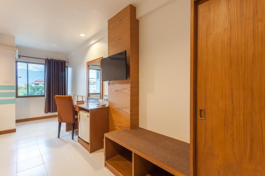 A side view of the room highlighting the desk, television, wardrobe and window.