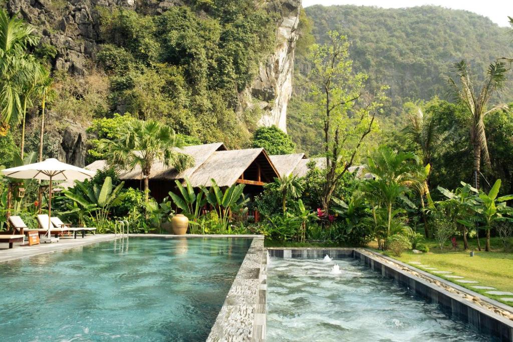 a pool in a resort with a mountain in the background at Tam Coc Golden Fields in Ninh Binh