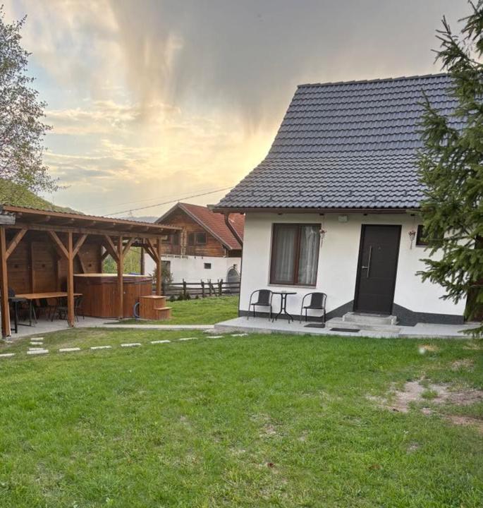 a house with two chairs and a table in a yard at Margaréta kulcsosház in Sub Cetate