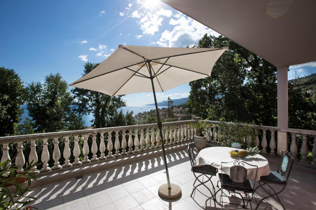 a table and chairs with an umbrella on a balcony at Apartments Green Garden in Opatija