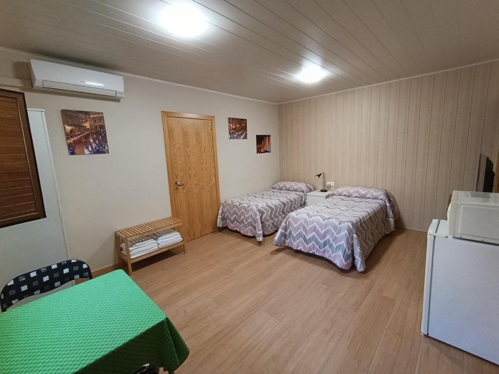 a room with two beds and a table and a refrigerator at Habitación independiente II en Casa Rural Javier in Valmuel