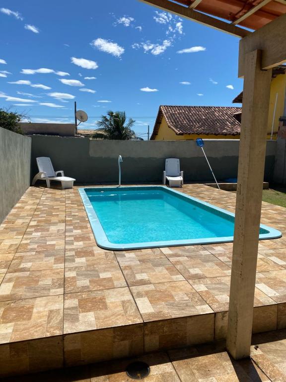a swimming pool on a patio with two chairs next to it at Refugio Paraiso in Arraial do Cabo