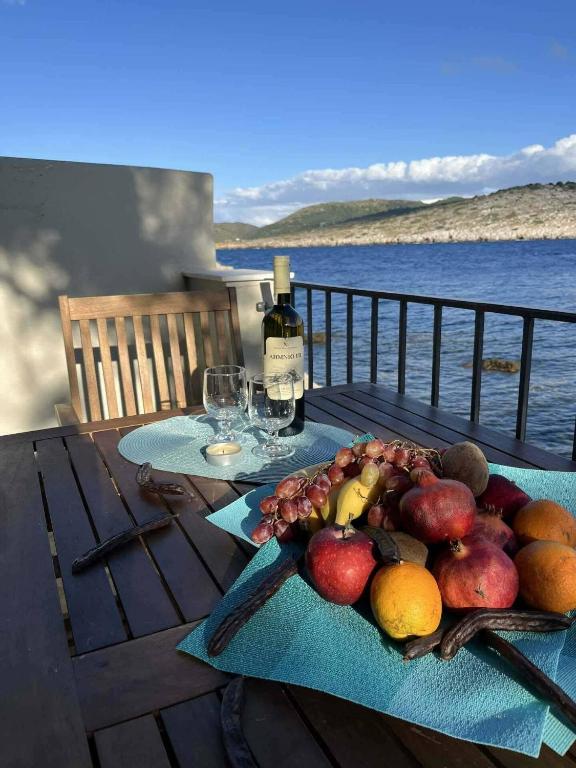 a table with a plate of fruit and wine bottles at Sunrise View in Kardámyla