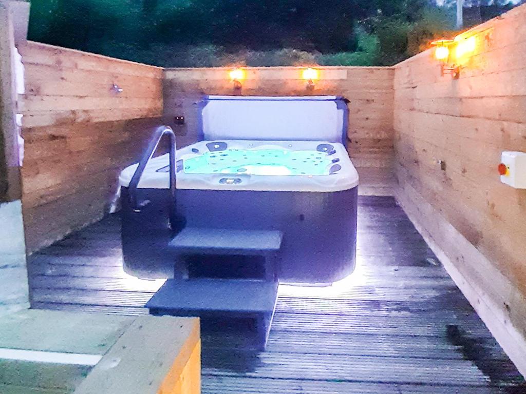 a bath tub sitting on a wooden deck with lights at Hilbre in Strachur