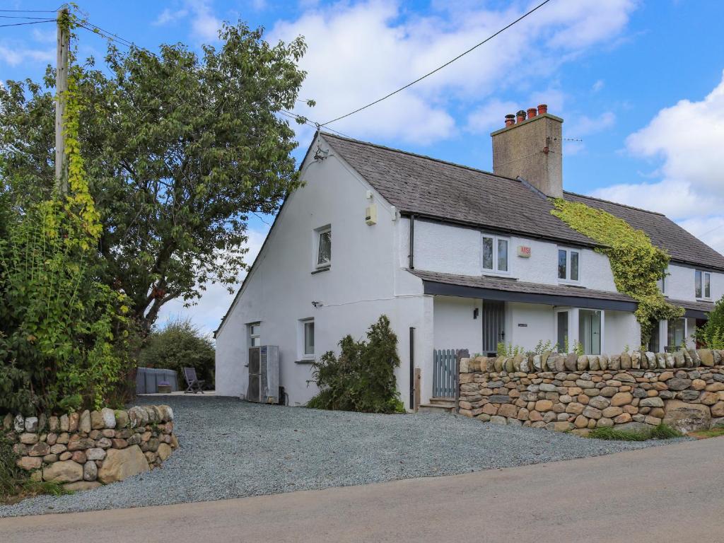 a white cottage with a stone wall at Pencefn Cottage in Llanddeiniolen