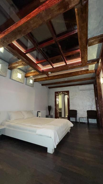 a large white bed in a room with wooden ceilings at Vendi Grand Square Residence in Sibiu