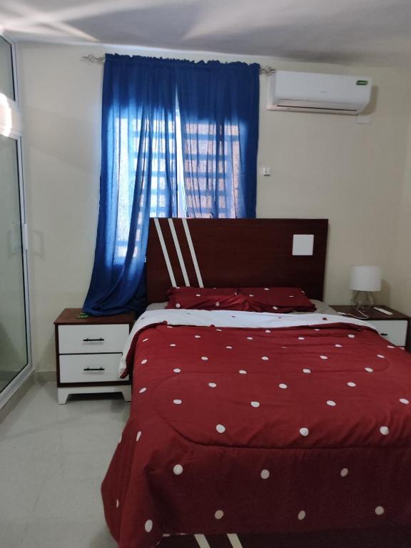 a bedroom with a red bed and blue curtains at Casa Nury in Santo Domingo