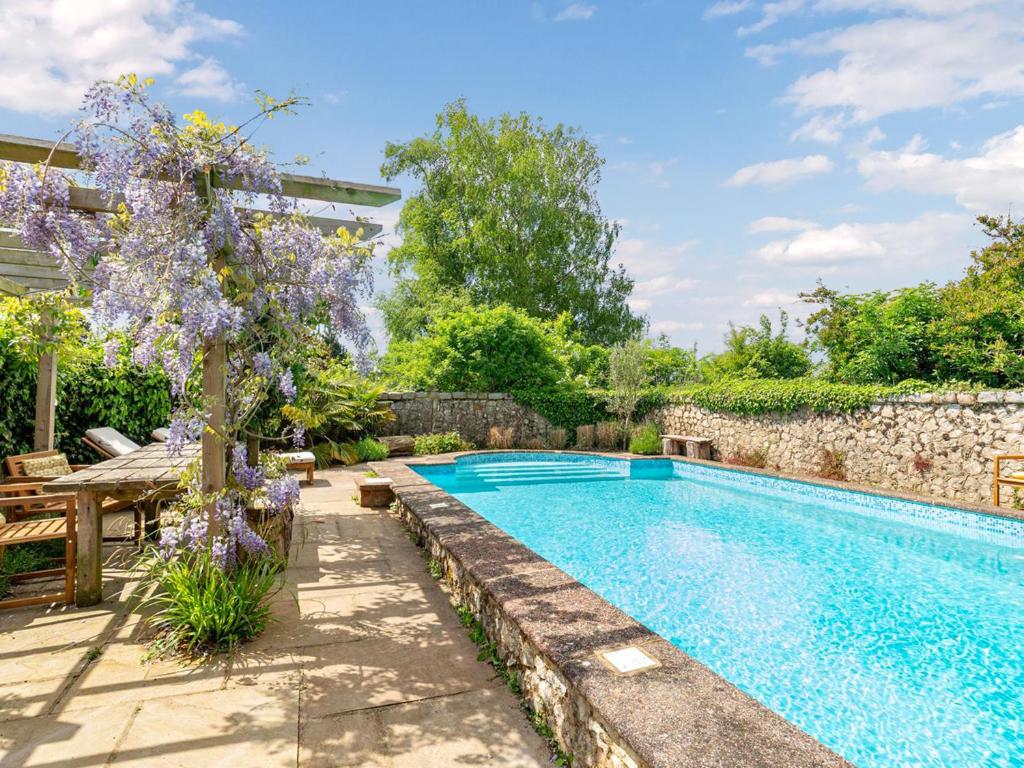 a swimming pool in a garden with a tree and purple flowers at Wren - Uk50152 in Stalisfield