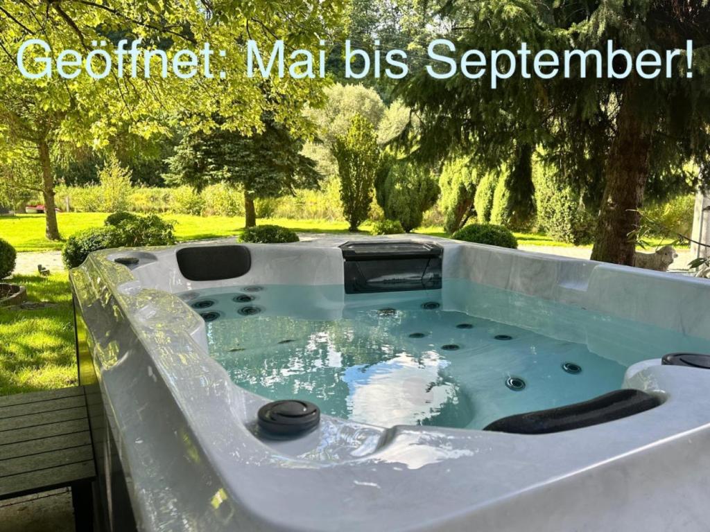 a jacuzzi tub in a garden with the words godfatherma b at Apartment direkt an der Waldnaab in Neustadt an der Waldnaab
