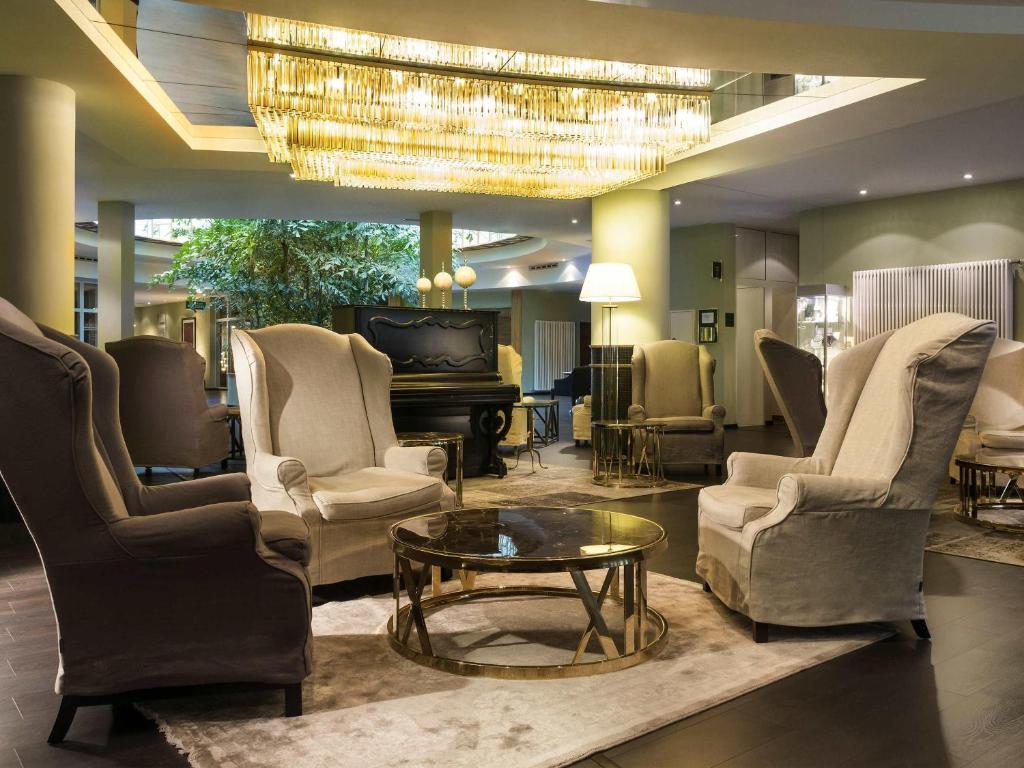 a lobby with chairs and a table and a chandelier at Congress Hotel Weimar by Mercure in Weimar
