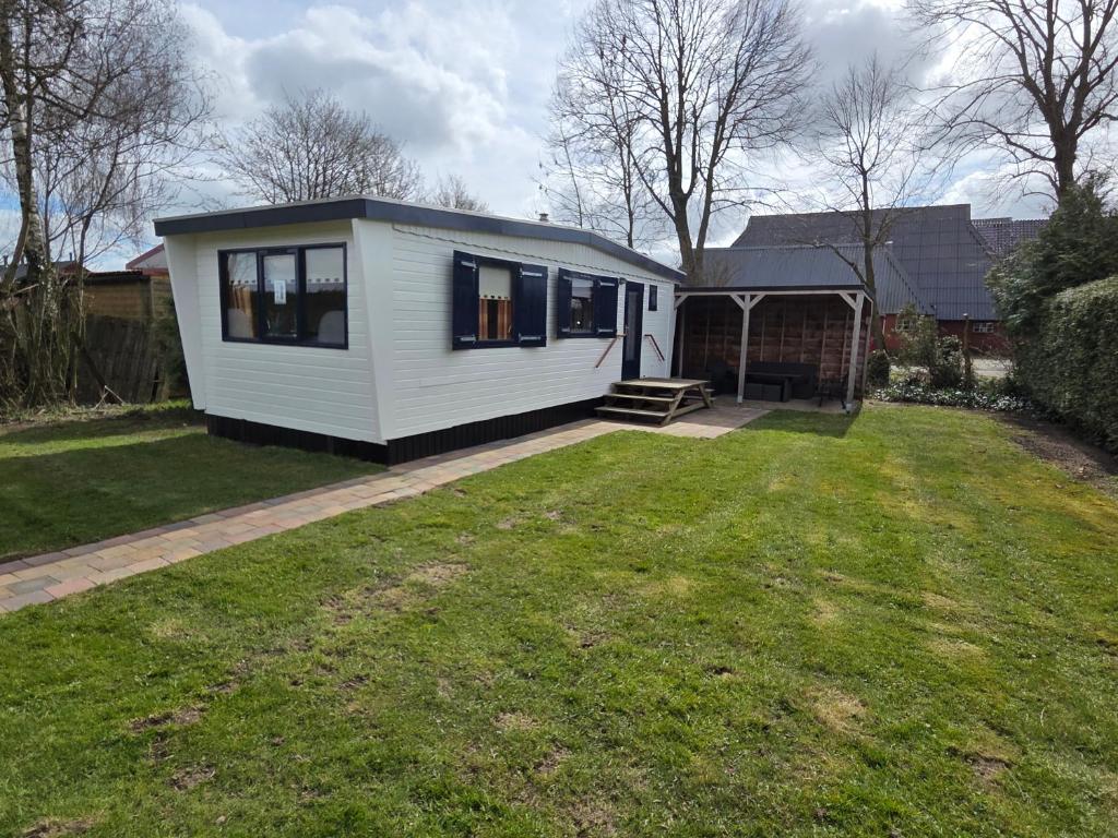 a small white tiny house in a yard at De Greidefûgel in Westergeest