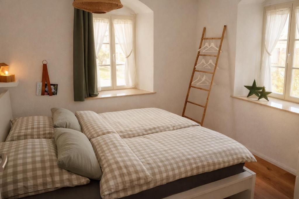 a bedroom with a bed and a ladder and windows at Gutshof 1600 in Hohnstein
