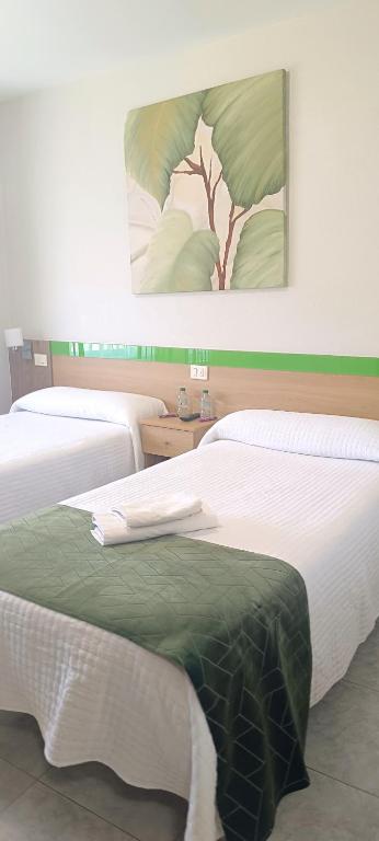 two beds in a room with a green blanket on them at Pension Casa Curro in Palas de Rei