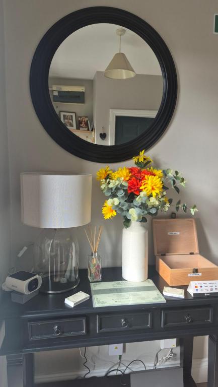 a table with a vase of flowers and a mirror at Brady Accommodation in Monaghan