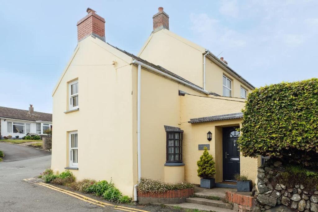 a white house with a black door on a street at Charming Upper Solva Cottage by Beaches and Harbour in Solva