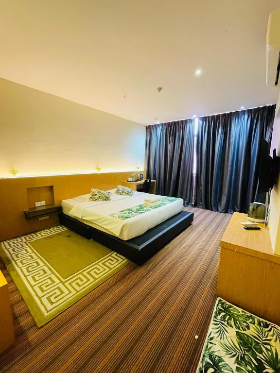 a bedroom with a large bed with blue curtains at Melaka City Hotel in Malacca