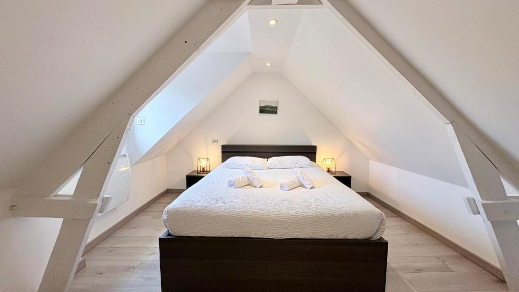 a bedroom with a white bed in the attic at Le Nid Des Grands Geais in Le Crotoy