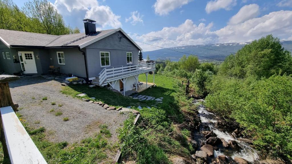 a small blue house with a porch next to a river at Leilighet på Bekkeli, Beito. in Beitostøl