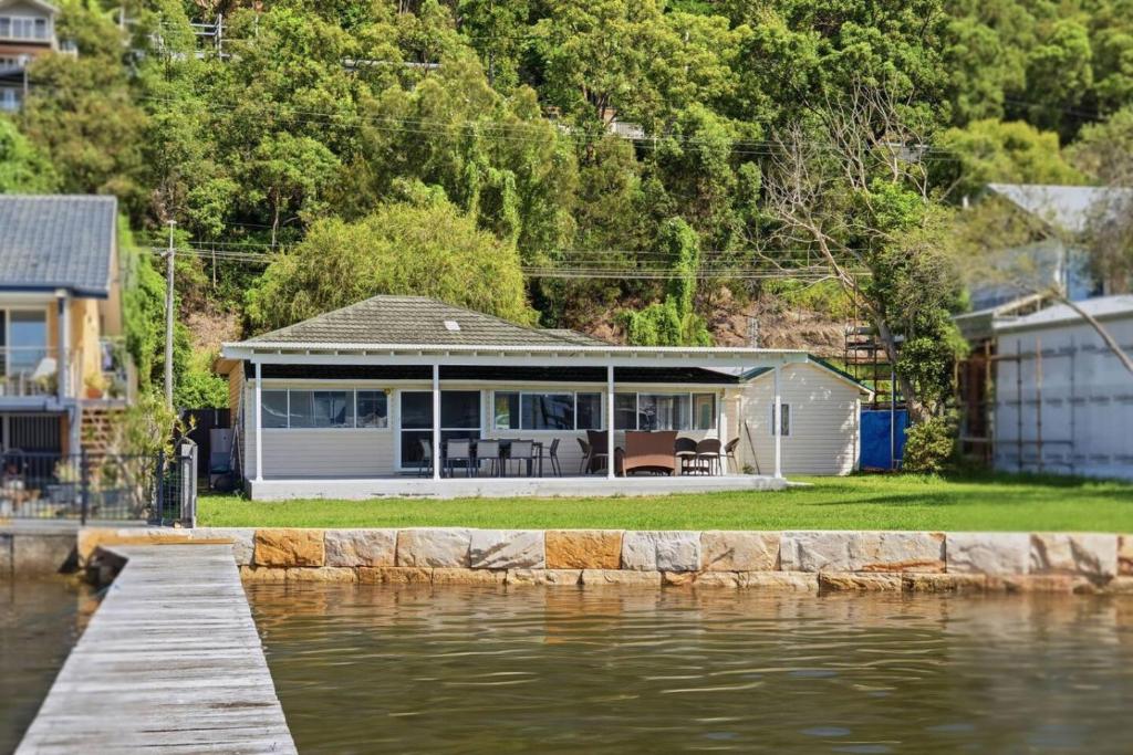 a house with a dock next to a body of water at Central Coast Waterfront 2BR with Jetty Access in Koolewong