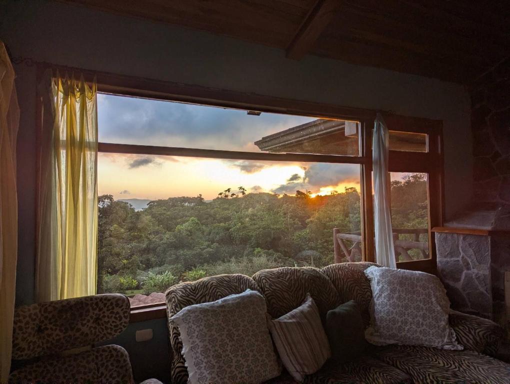 a living room with a couch and a large window at Villa Siempre Aventura in Nuevo Arenal