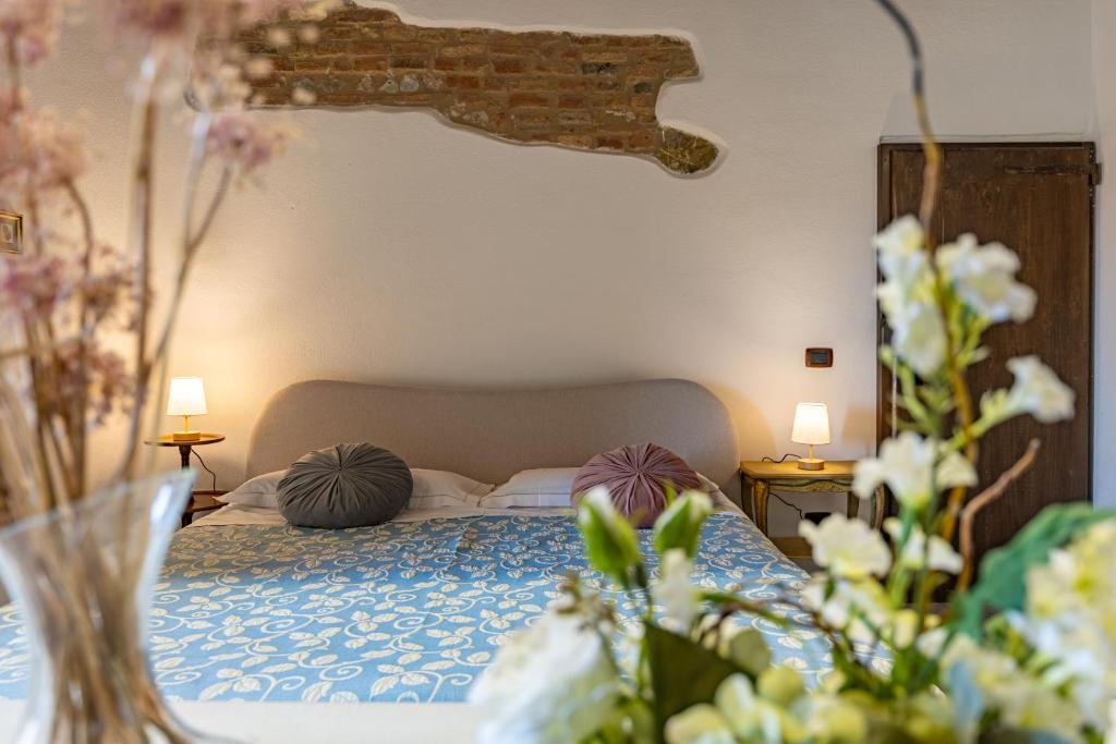 a bedroom with a bed with pillows and flowers at Pociano 1863 - Country House with Stunning view of Siena in Monteroni dʼArbia