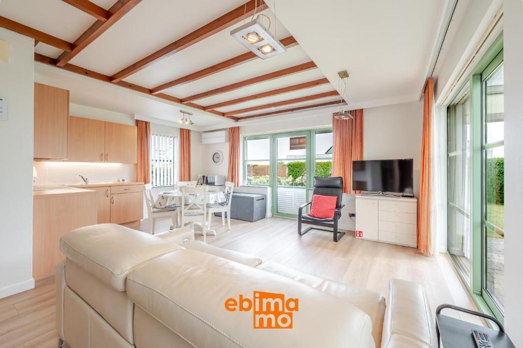 a living room with a white couch and a kitchen at Nieuwendamme 69 with pool and parking in Nieuwpoort