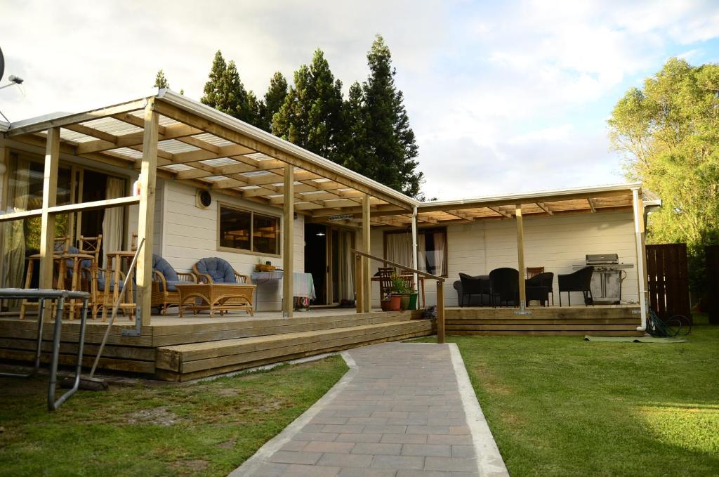 a house with a large wooden deck in the yard at Tony's Lodge in Turangi