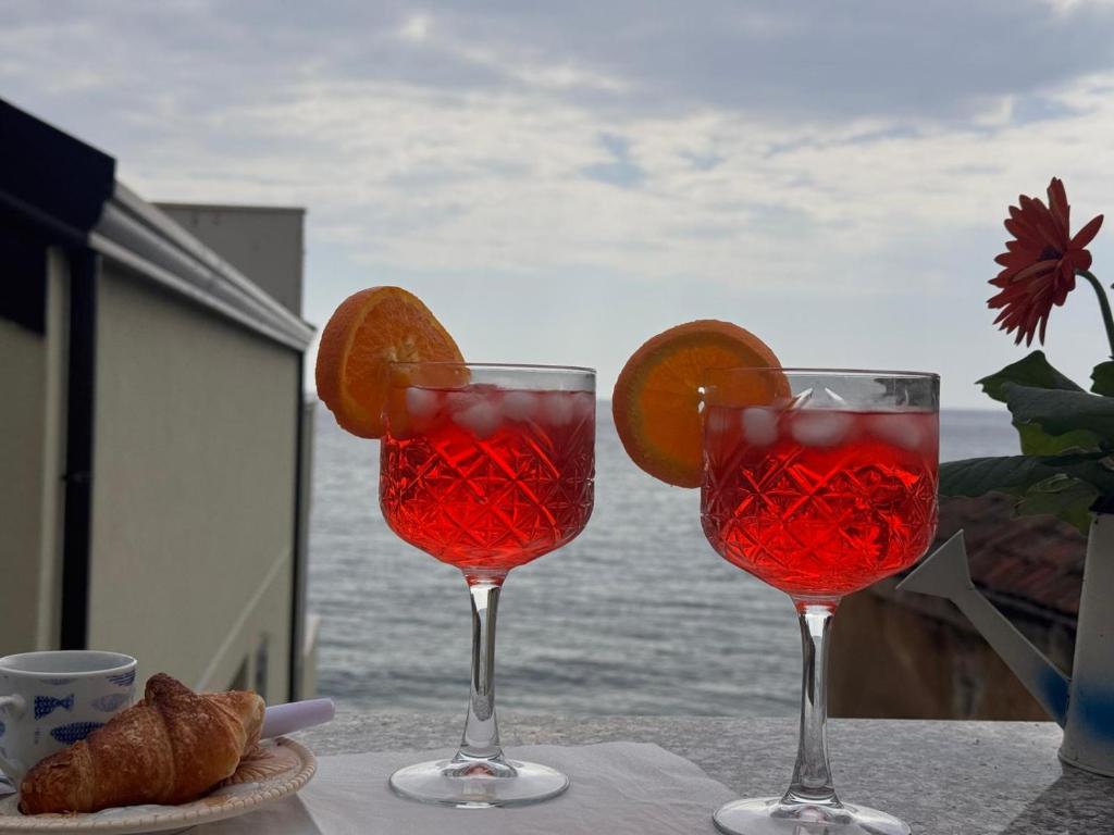 two wine glasses with oranges and croissants on a table at Bella Tao Apart in Taormina
