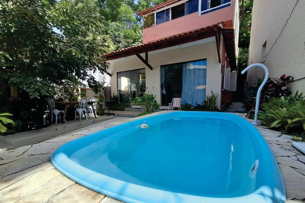 a blue swimming pool in front of a house at Residencial Costa Loft in Angra dos Reis