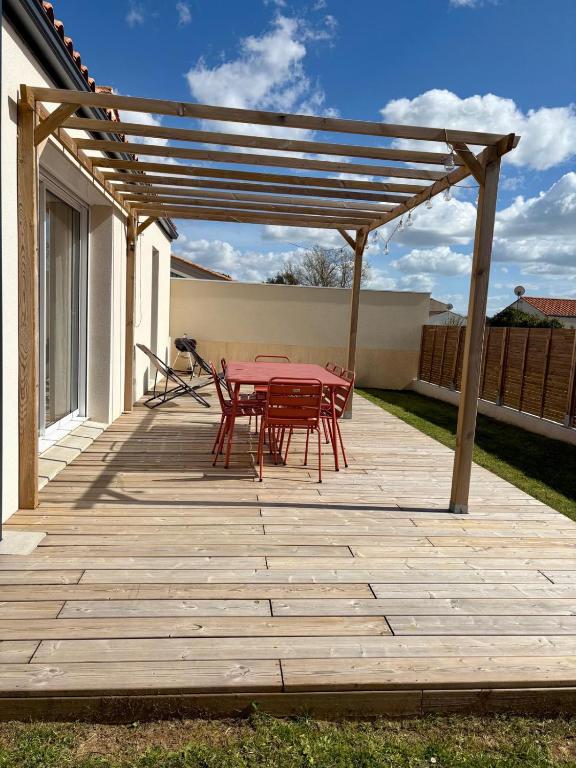 a patio with red tables and chairs under a pergola at Casa Côme - Maison climatisée - Tout à pied ! in Saint-Vincent-sur-Jard